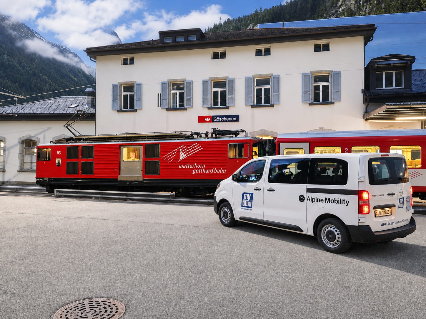 MG-Bahn steht vor Haltestelle Göschenen und mybuxi Rufbus steht davor